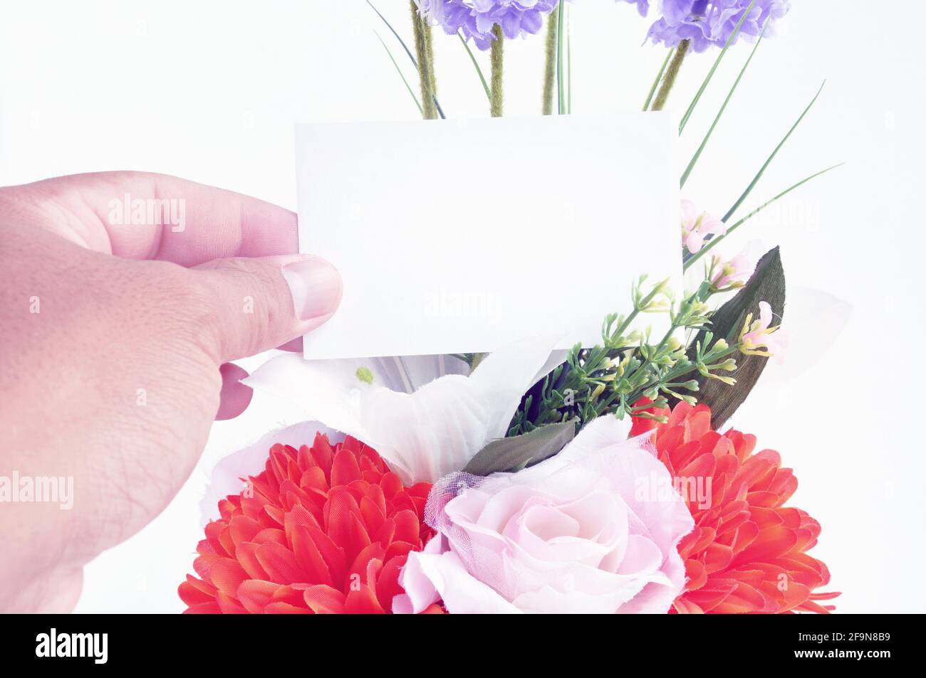 Hand hält leere Tag-Karte auf Blumenstrauß - retro Stilvolles Licht Stockfoto