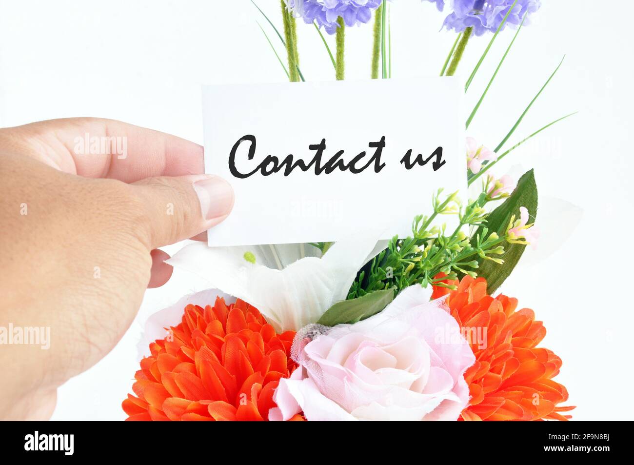 Blumenstrauß mit „ Contact US “ auf der Tag-Karte Stockfoto