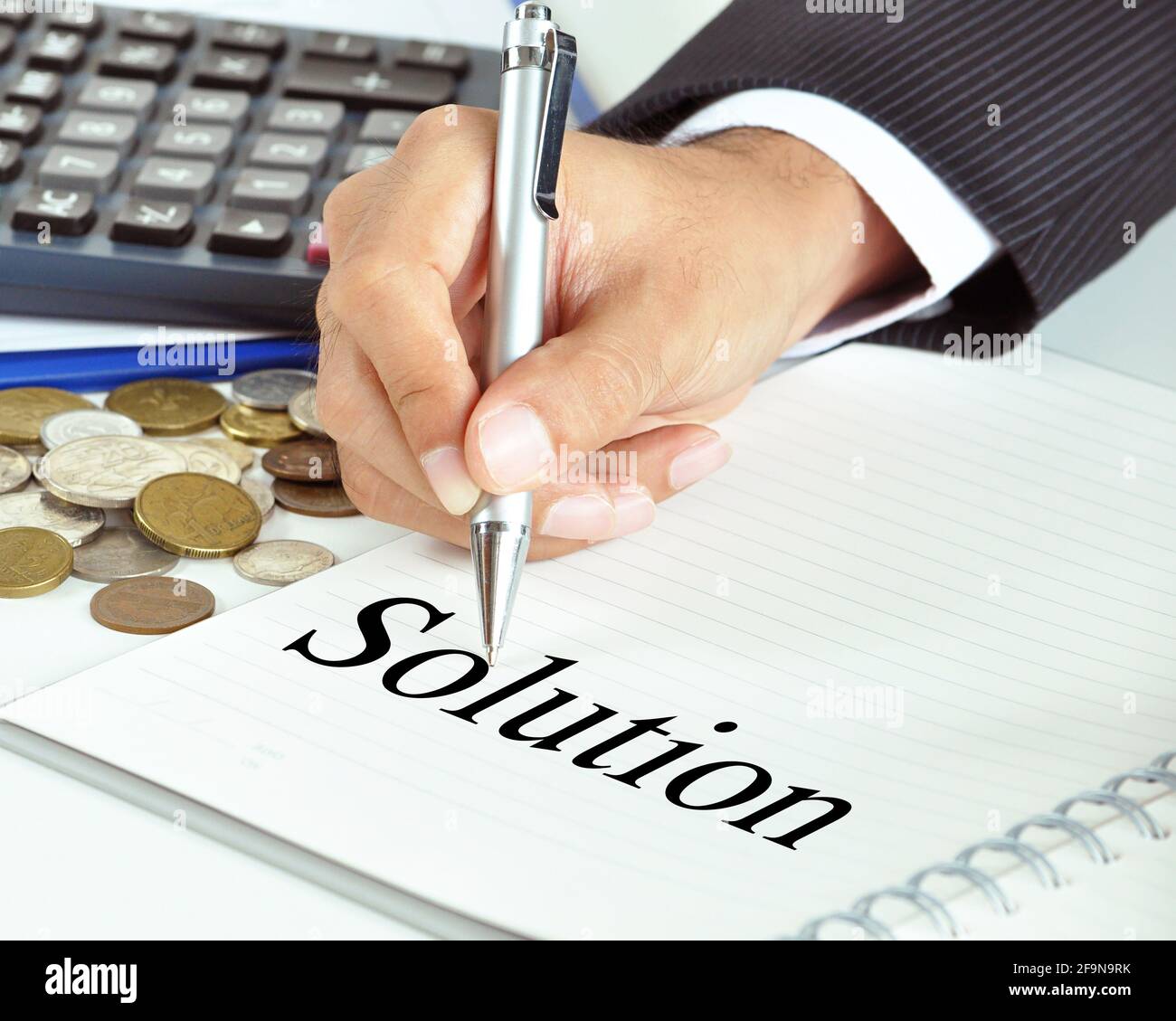 Hand mit dem Stift, der auf das Lösungswort auf dem Papier zeigt - Finanz- und Geschäftsreferat Stockfoto