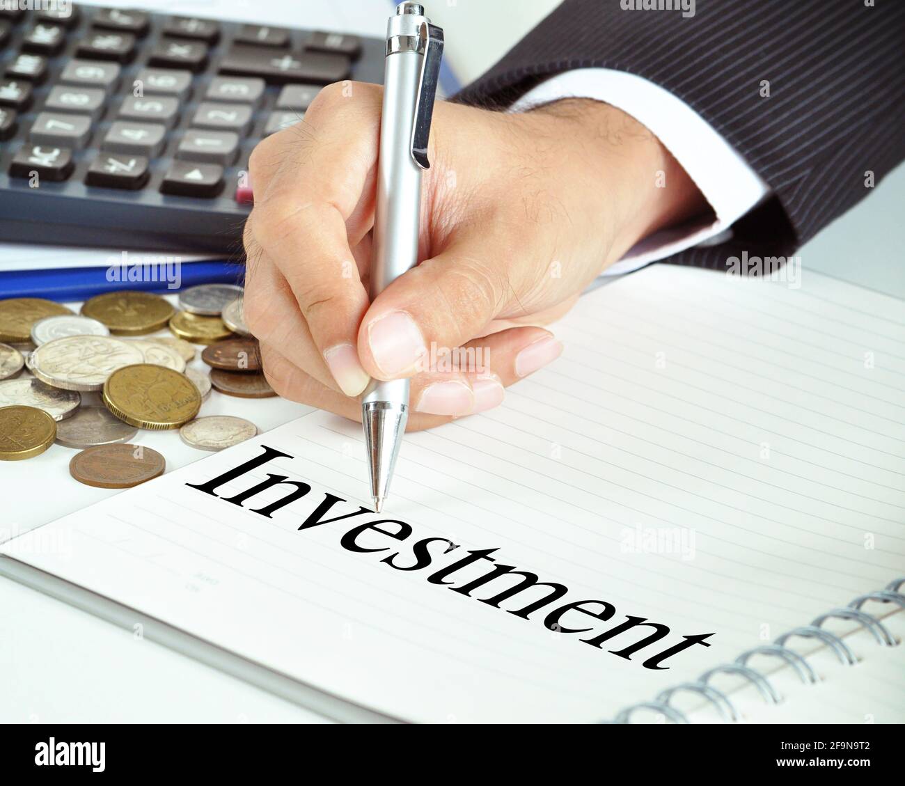 Hand mit Stift, der auf das Wort „Investition“ auf dem Papier zeigt - Finanz- und Geschäftskonzept Stockfoto