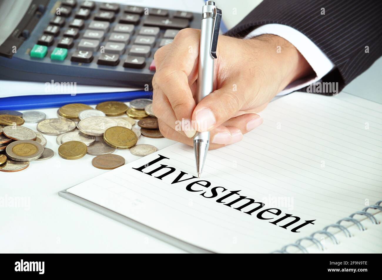 Hand mit Stift, der auf das Wort „Investition“ auf dem Papier zeigt - Geschäfts- und Finanzkonzept Stockfoto