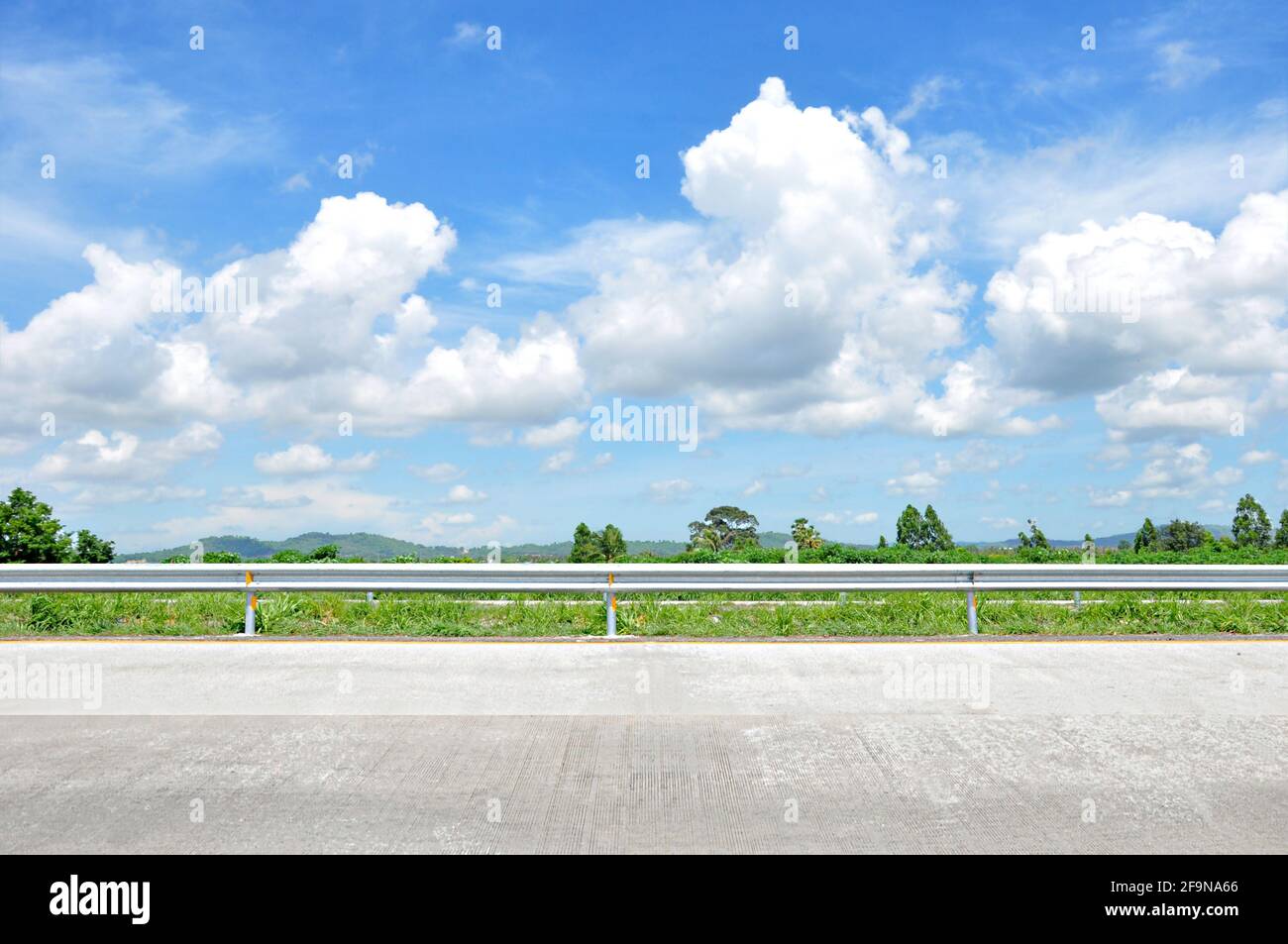 Schöner Blick auf die Straße mit grüner Natur und wolkenblauem Himmel Bachground Stockfoto
