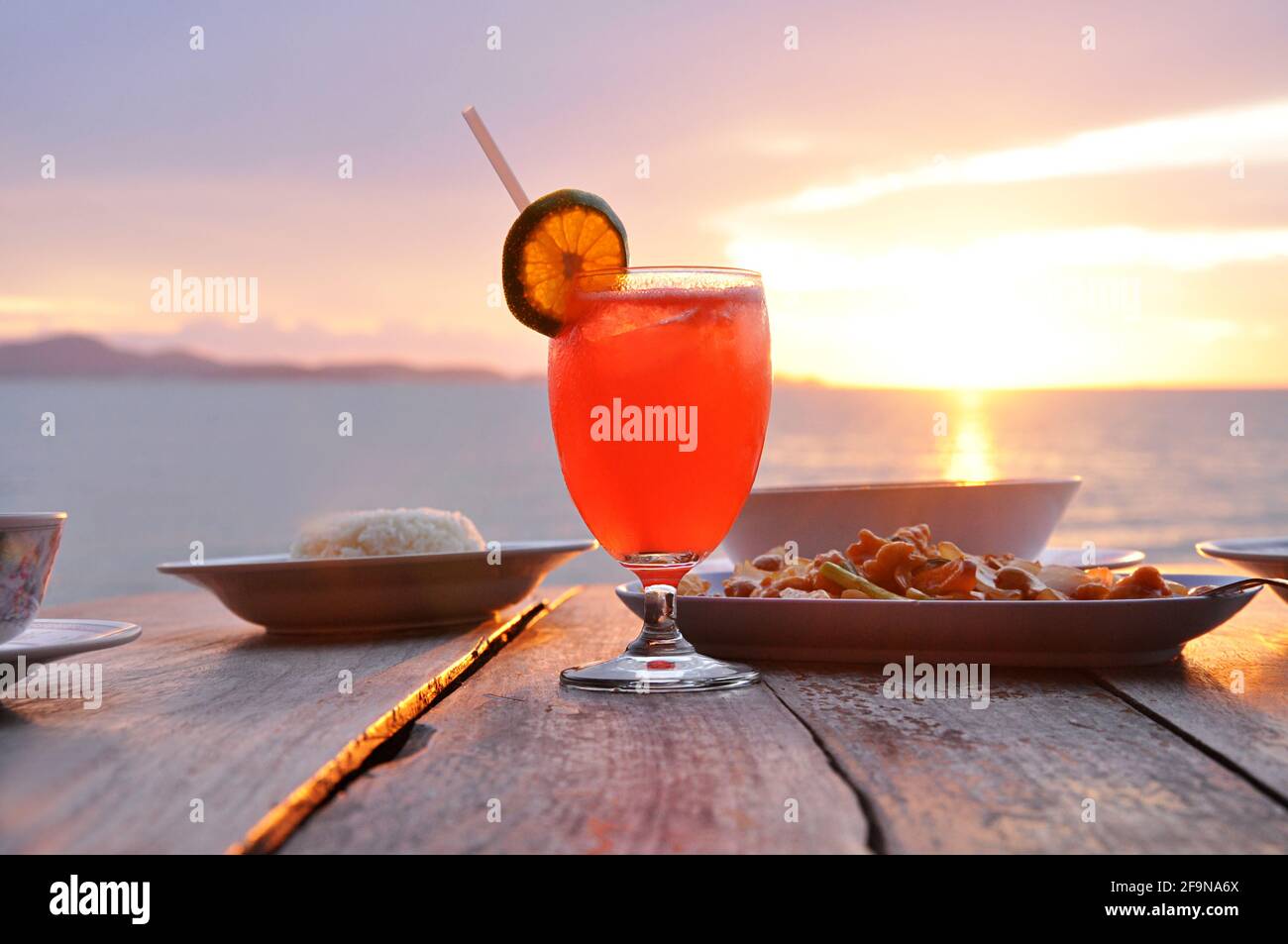 Cocktailgetränk mit asiatischen Speisen auf altem Holztisch Und Meereswasser Hintergrund Stockfoto