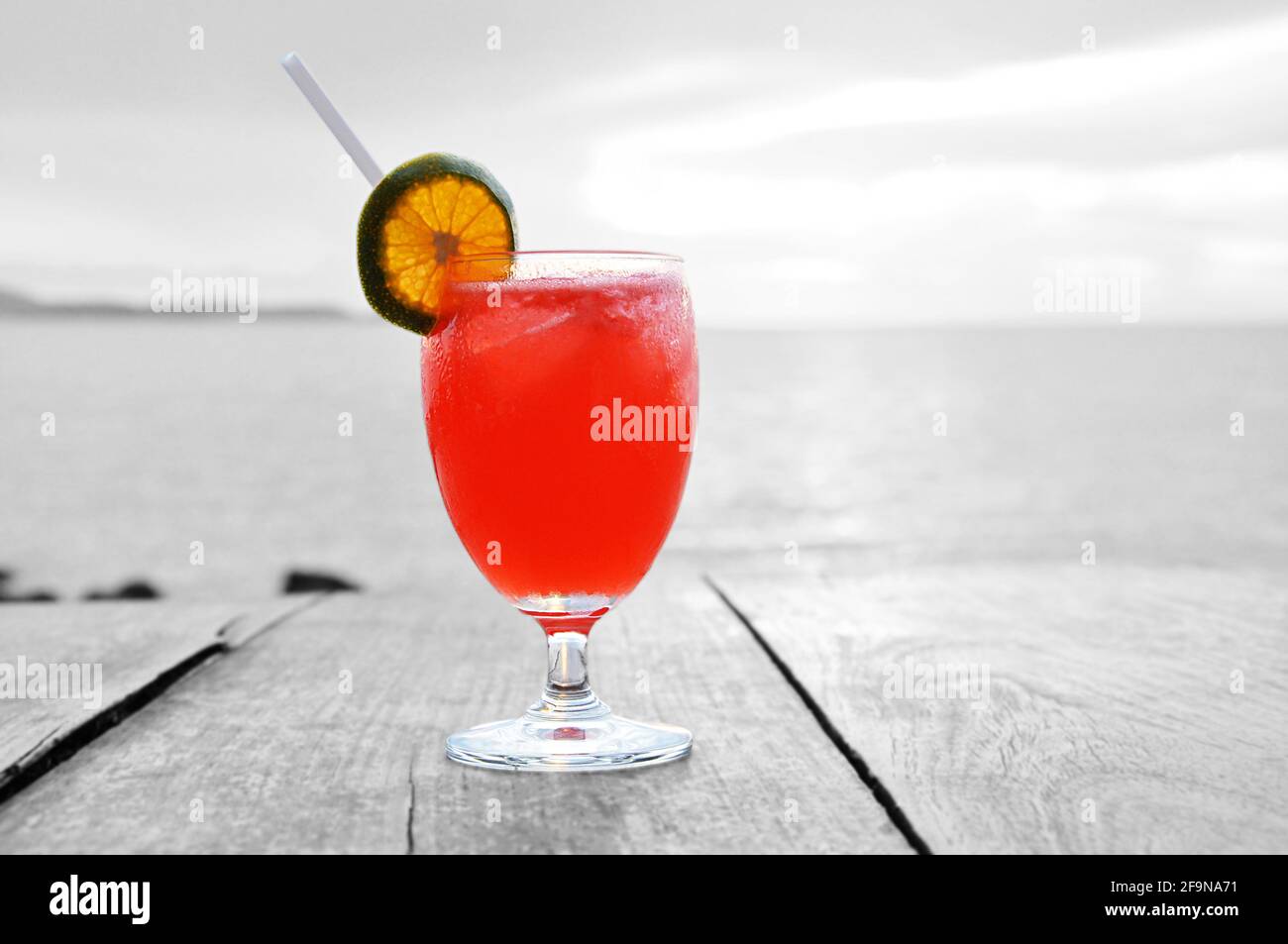 Cocktailgetränk mit Orangenscheibe als Beilage auf altem Holztisch und Meereswasser Hintergrund Stockfoto