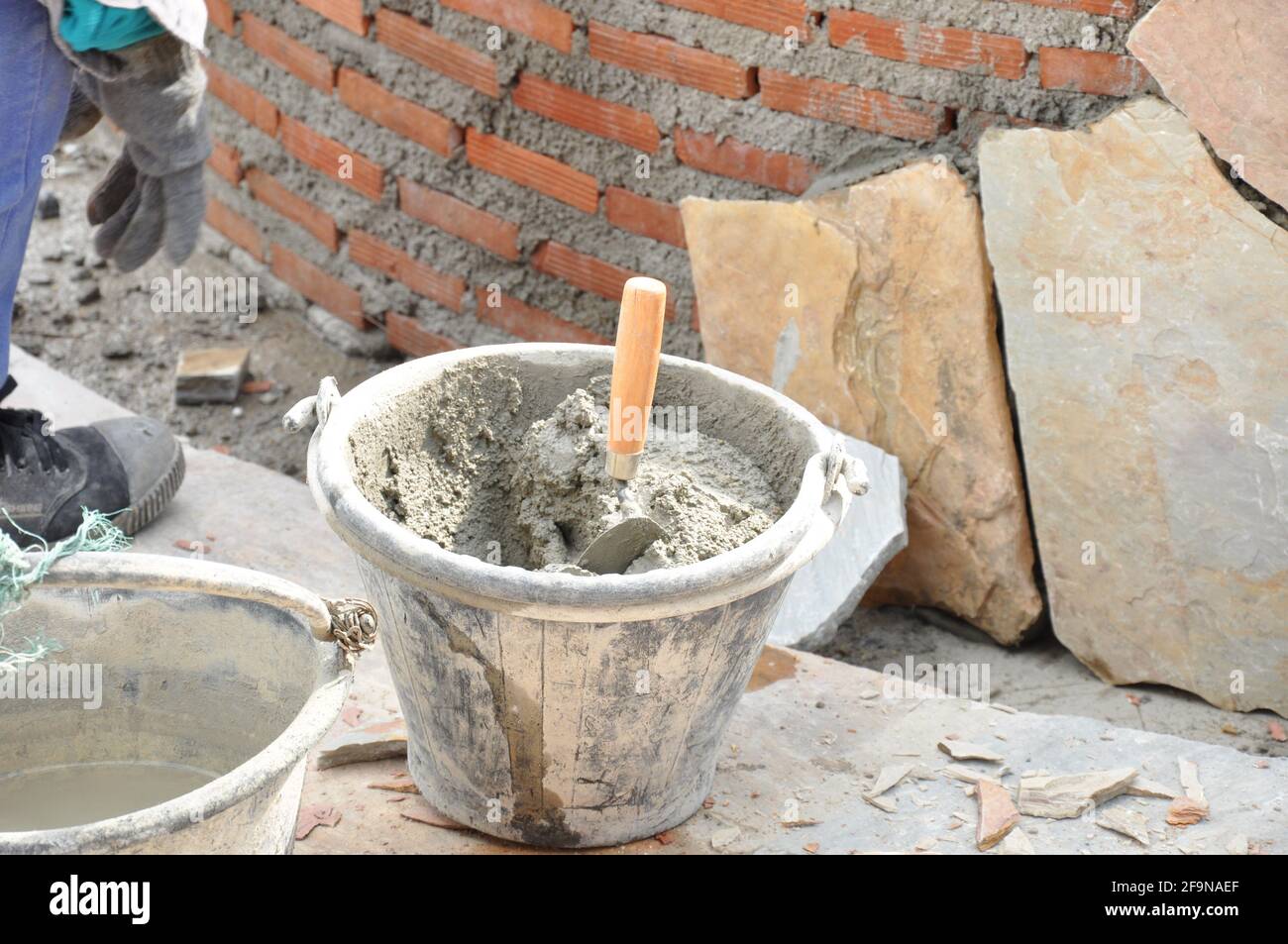 Eimer aus Mörtel mit Kelle neben dem Bau einer Ziegelmauer Stockfoto