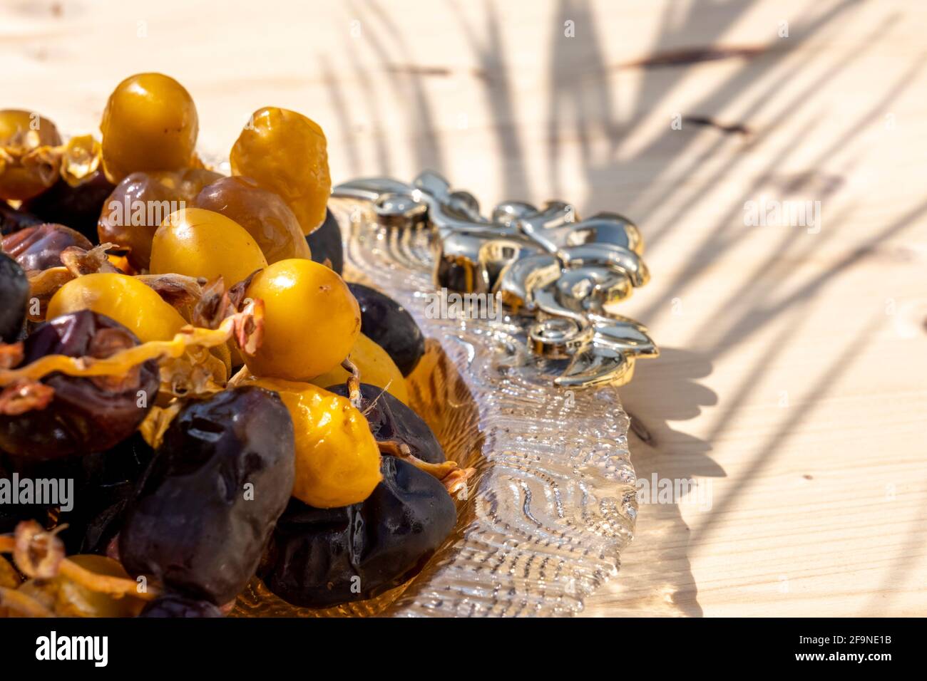 Religiöse muslimische Fastenfest und heiligen Monat Ramadan Konzept: Viele süß braun und gelb getrockneten Dattdaten Früchte auf einem verzierten Teller. Holztisch. Stockfoto