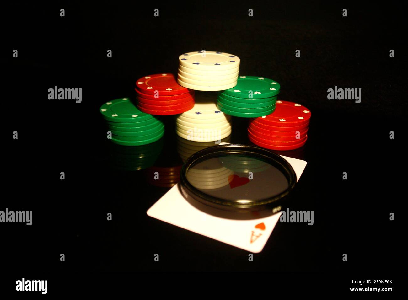 Stapel von Poker-Chips mit einer roten Herz-Karte, Fotofilter vorne und Reflexionen isoliert auf schwarz Stockfoto