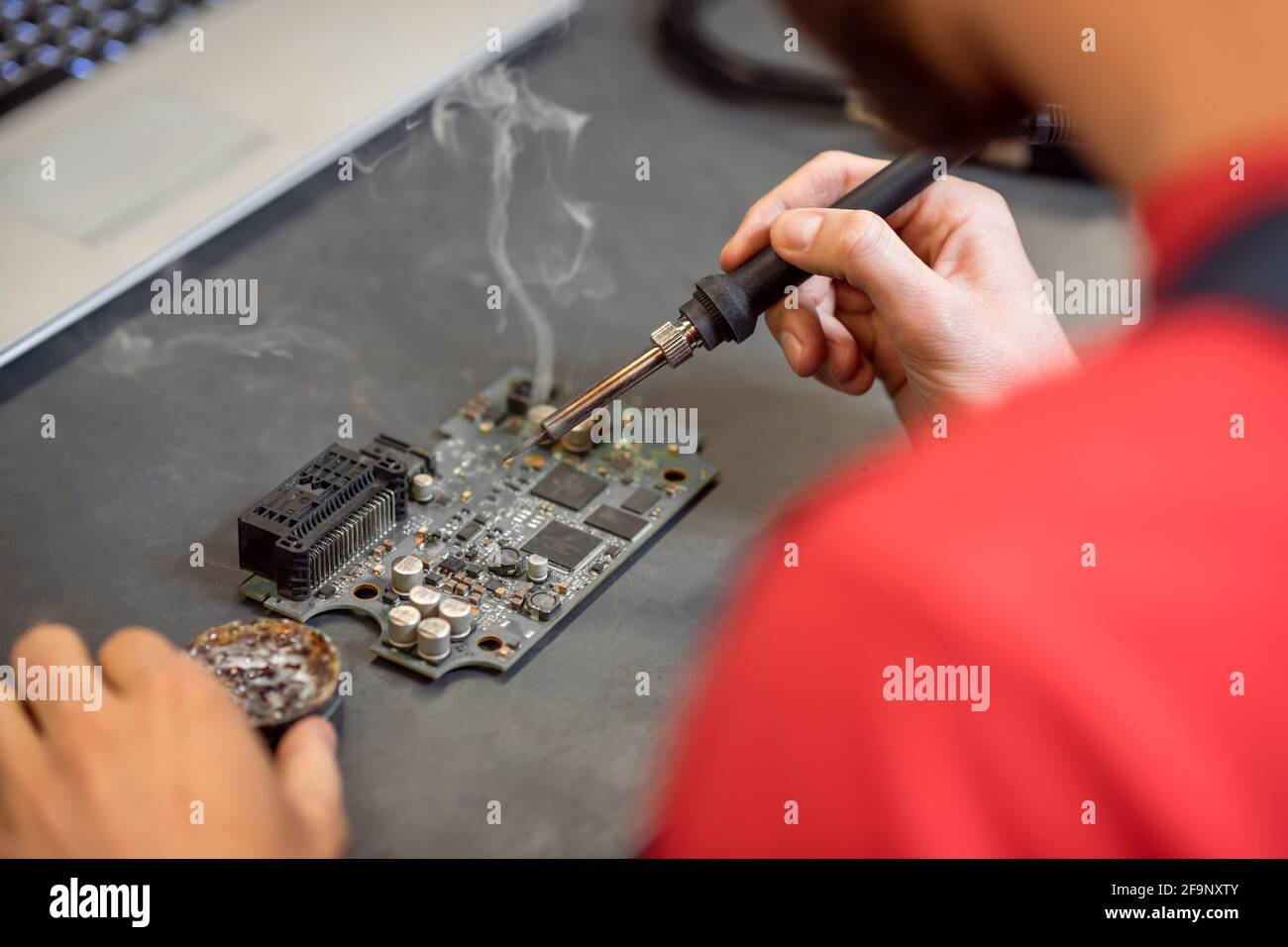 Hände von Menschen mit Lötkolben und Mikroschaltung Stockfoto