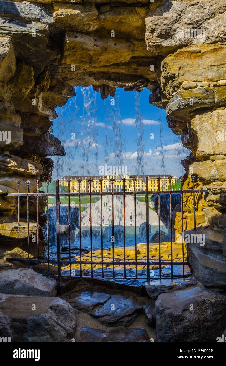 Blick auf das Schloss schoinbrunn in wien durch einen Wasserfall im Inneren des Hauptbrunnens. Stockfoto