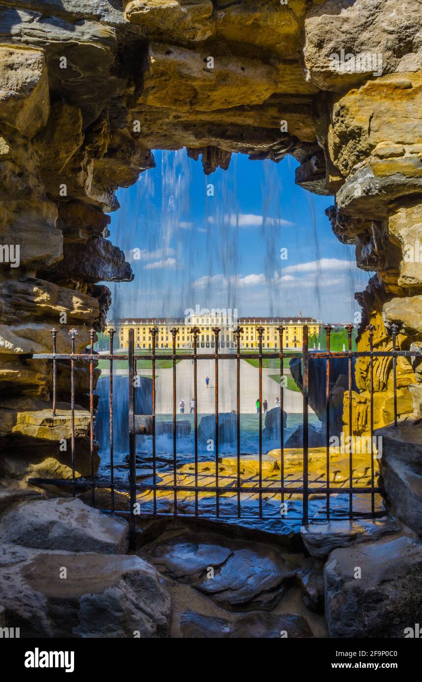 Blick auf das Schloss schoinbrunn in wien durch einen Wasserfall im Inneren des Hauptbrunnens. Stockfoto