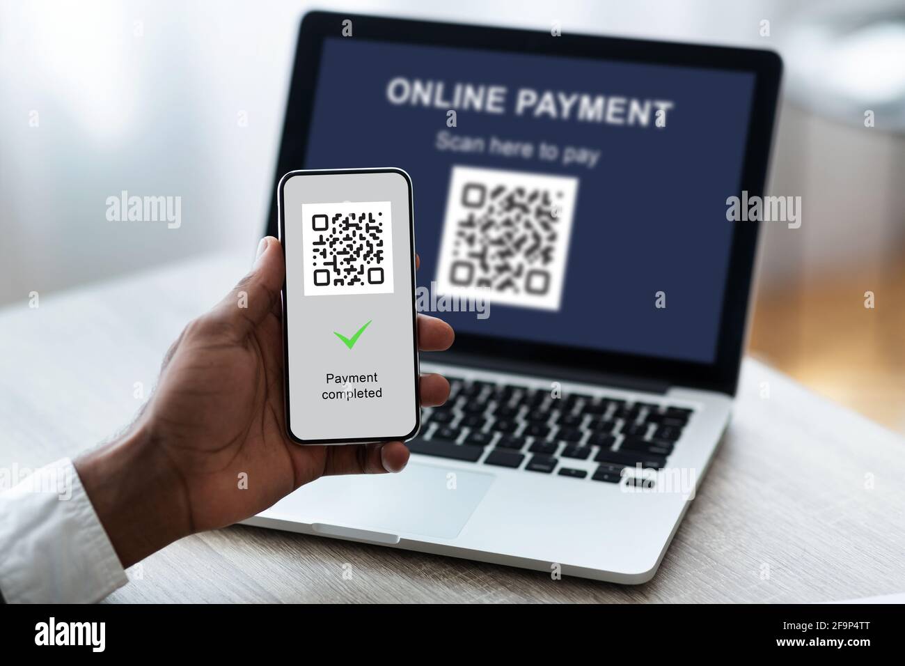 Nicht erkennbarer Geschäftsmann scannt Barcode per Smartphone vom Laptop Stockfoto