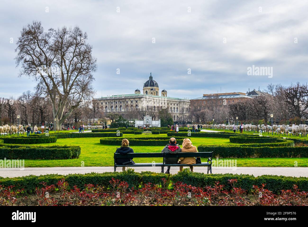 Im berühmten Volksgarten mit Naturkundemuseum vor dem Hintergrund in Wien, Österreich, sitzen Menschen auf einer Bank. Stockfoto