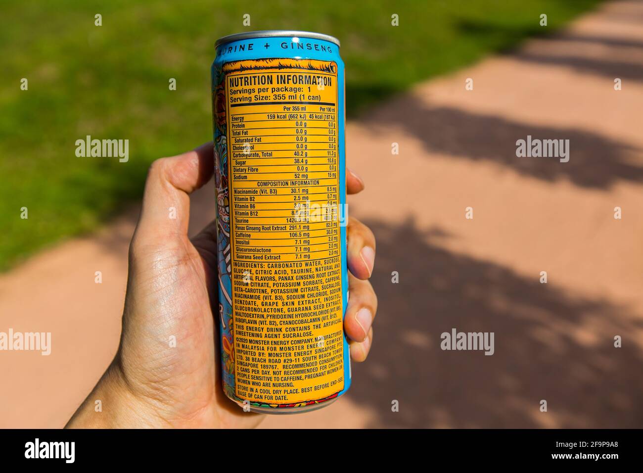 Eine Hand, die eine Monster Energy hält, kann trinken und Nährwertinformationen anzeigen. Stockfoto