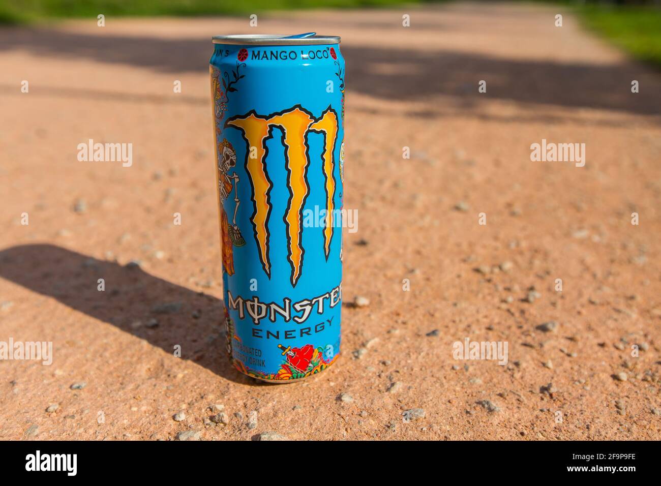 Eine Dose Monster Energy Drink auf dem Laufweg. Trink es für Energie, während du läufst und Geschichten erzählst. Licht und Schatten. Stockfoto