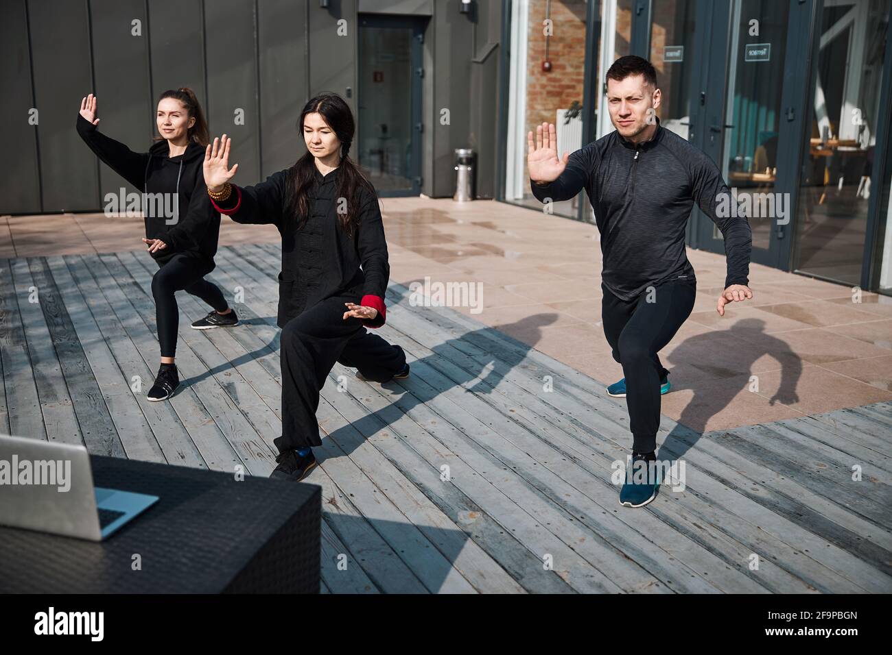 Kung Fu-Gruppe übt draußen mit Laptop-Bildern Stockfoto