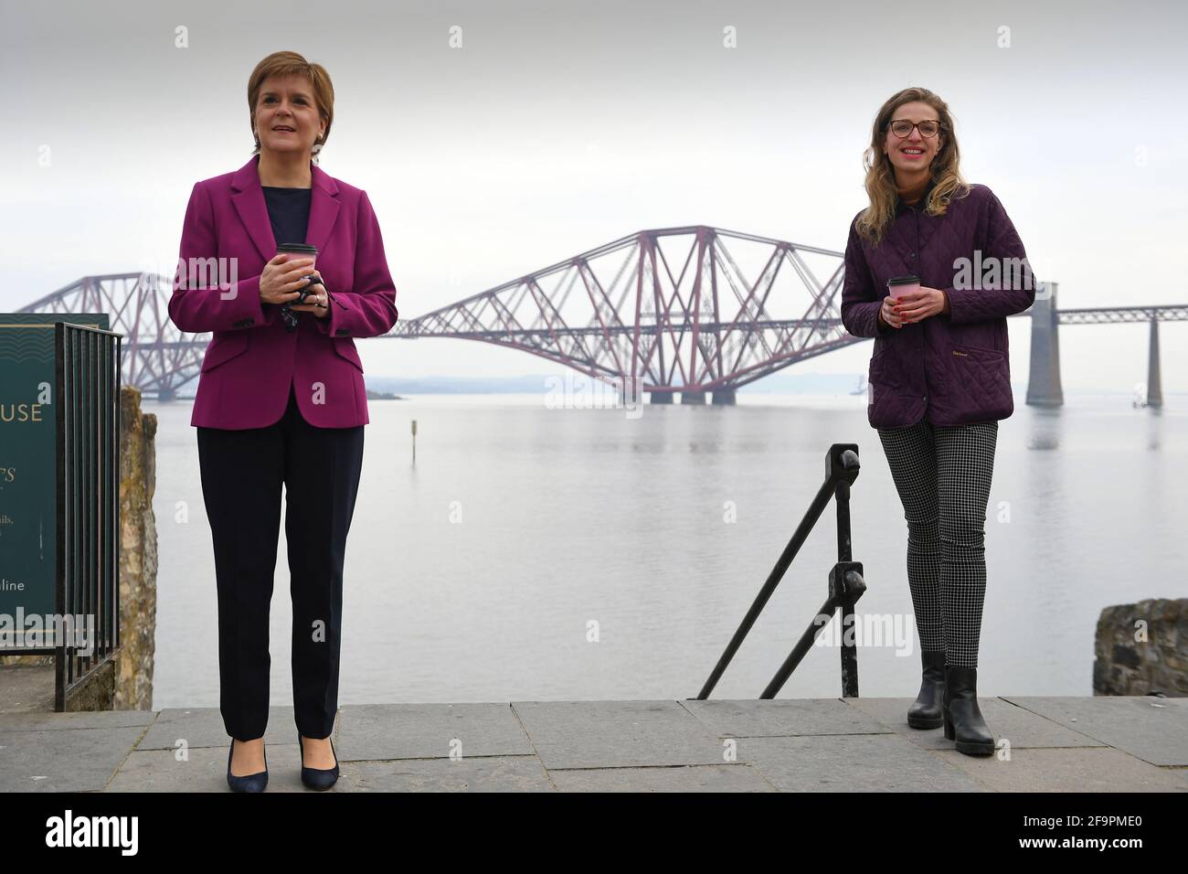 Schottlands erste Ministerin Nicola Sturgeon, Vorsitzende der Scottish National Party (SNP), mit der Kandidatin der Edinburgher Western Sarah Masson (rechts) neben dem Firth of Forth und der Forth Bridge, während sie während ihrer Wahlkampagne für die schottischen Parlamentswahlen in South Queensferry kämpft. Bilddatum: Dienstag, 20. April 2021. Stockfoto