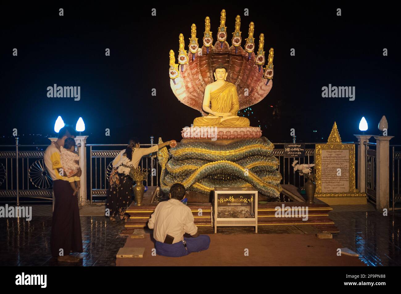 30.01.2017, Mawlamyine, Mon State, Myanmar - Gläubige vor einer beleuchteten Buddha-Gestalt in der Kyaikthanlan-Pagode, dem höchsten buddhistischen pa der Stadt Stockfoto