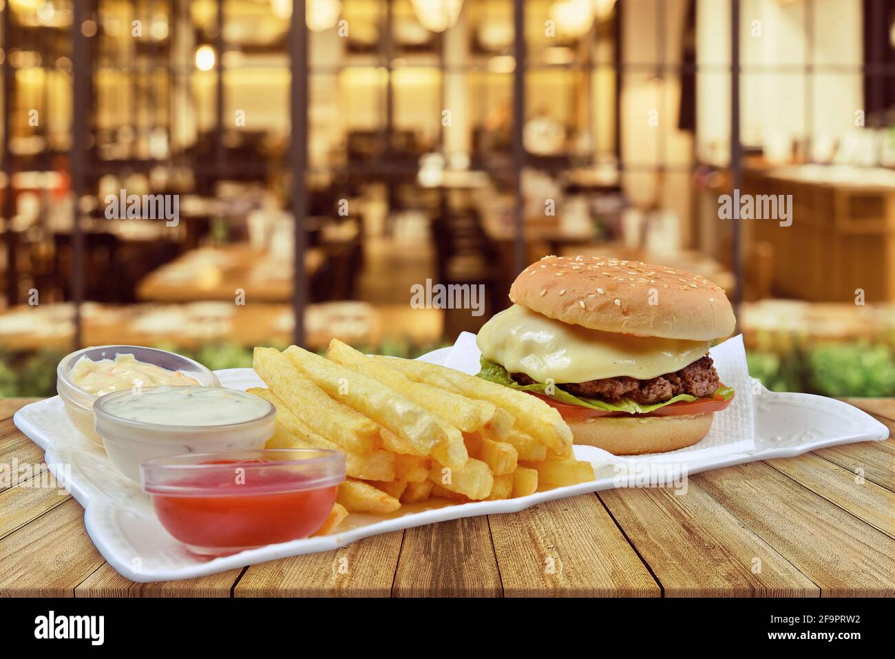 Hamburger mit Käse und Tomaten mit pommes frites. Ketchup und Mayonnaise, Restauranthintergrund, Restaurantkonzept Stockfoto