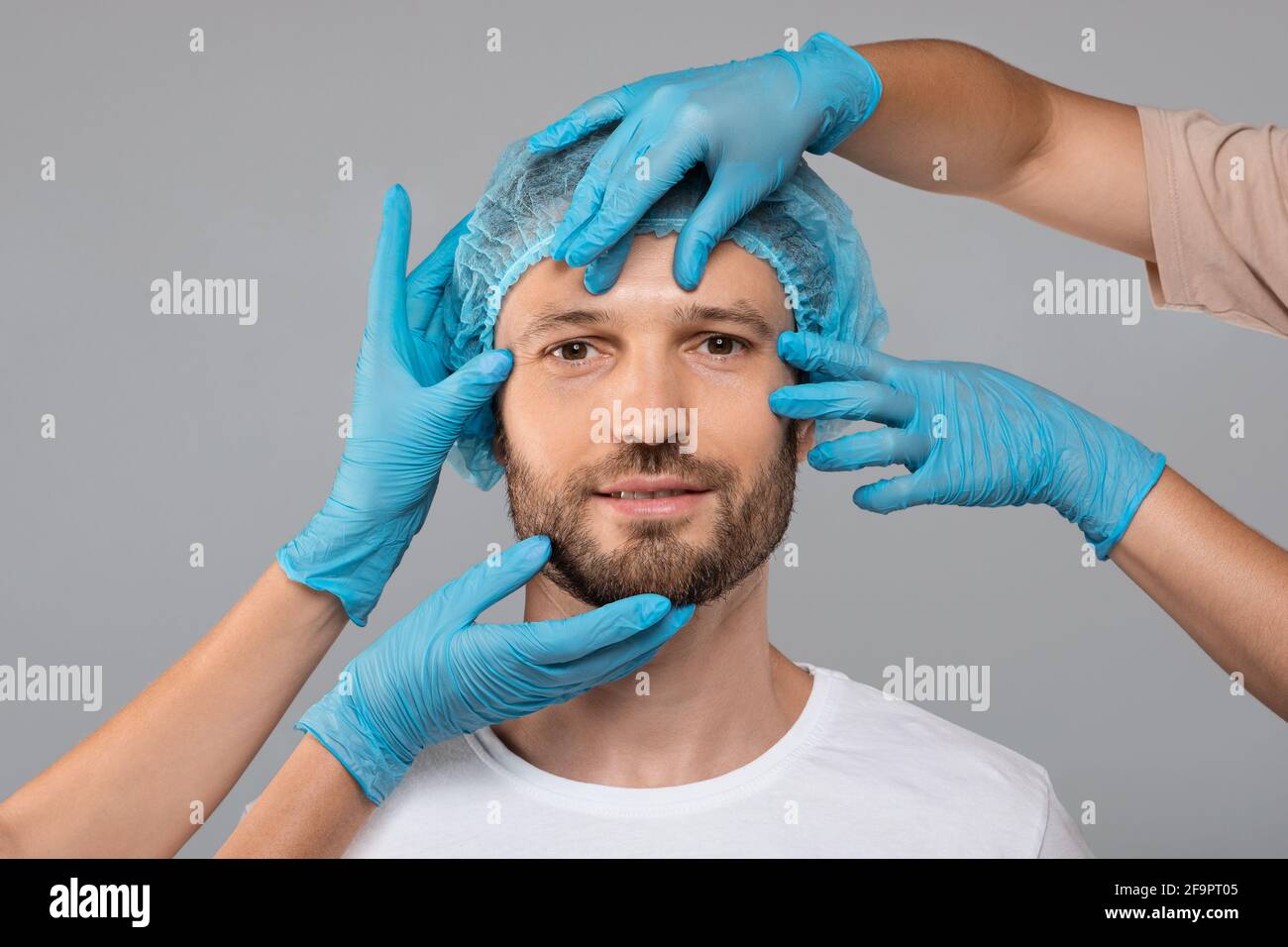 Ärzte Hände in Schutzhandschuhen berühren Mann Gesicht vor der Operation Stockfoto