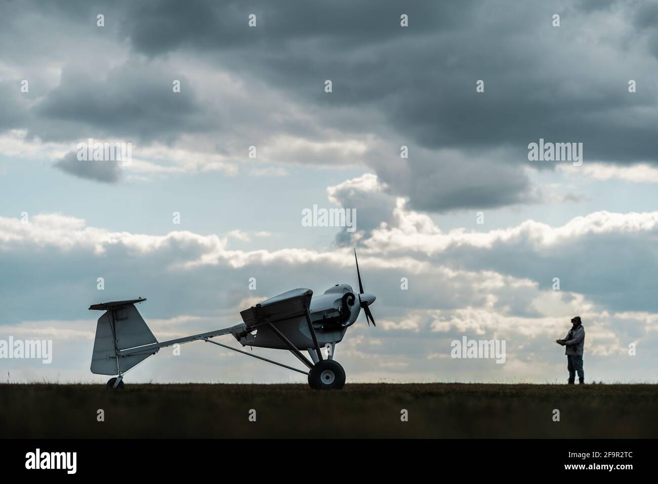 Pilot mit Fernbedienung Ebene für landwirtschaftliche Spritzeinspritzung starten bei Flugplatz Stockfoto