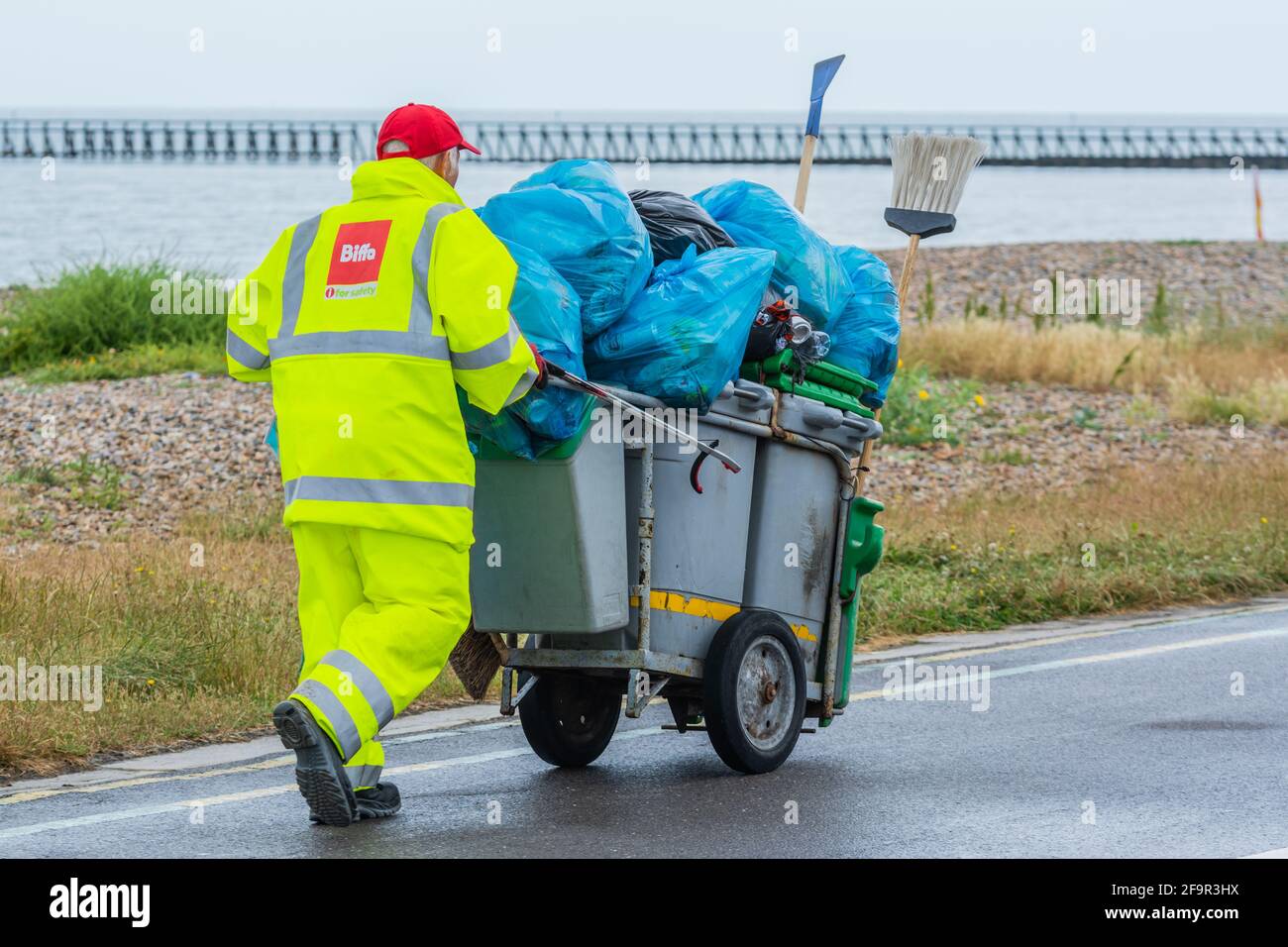 Biffa-Mitarbeiterin schiebt Mülleimer und sammelt Müll auf der Promenade in Littlehampton, West Sussex, England, Großbritannien. Stockfoto