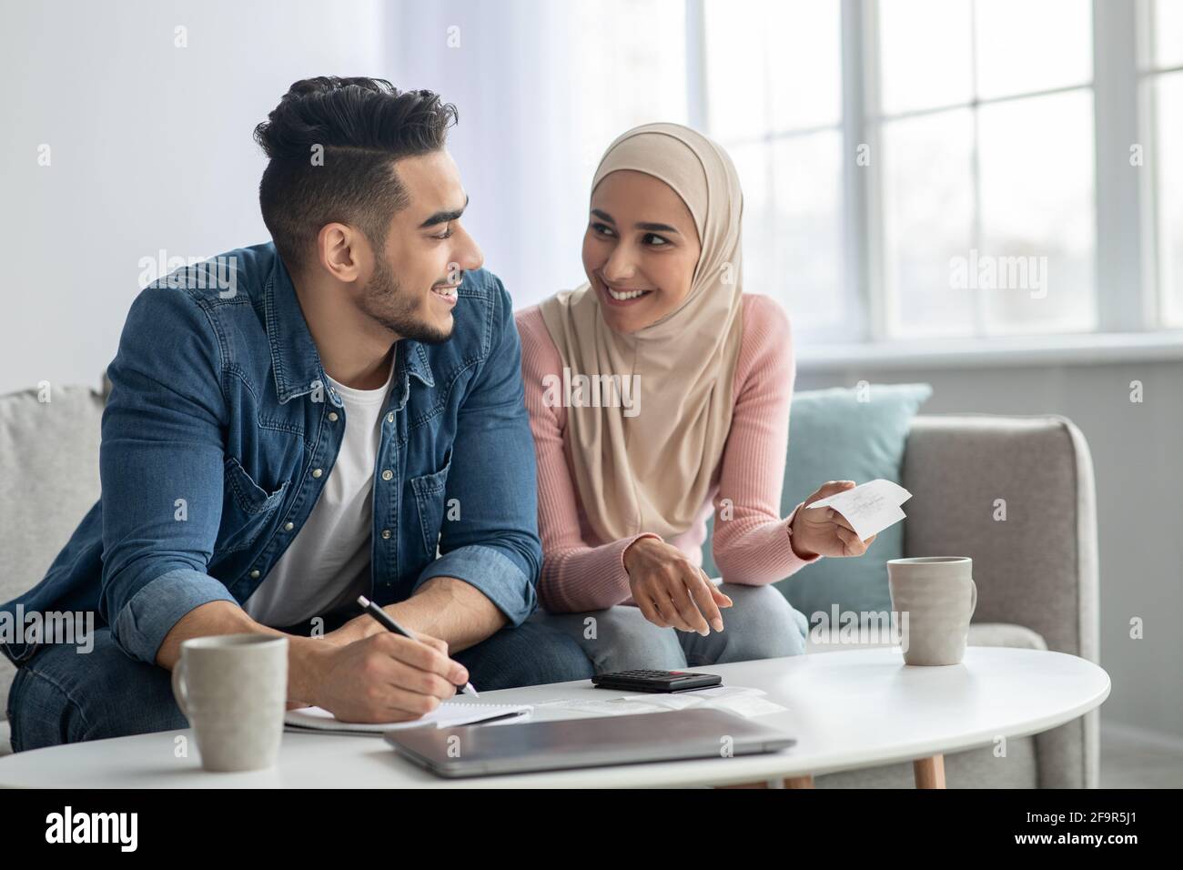 Positive muslimische Familie, die ihre Verauslagungen zählt, sich wohlhabend fühlt Stockfoto