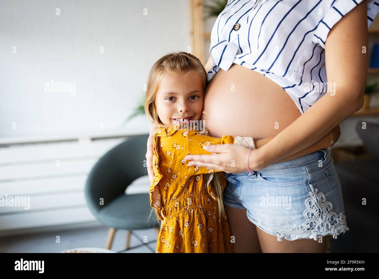 Schöne schwangere Frau mit süßen Tochter. Schwangerschaft, Familie, Liebe. Stockfoto