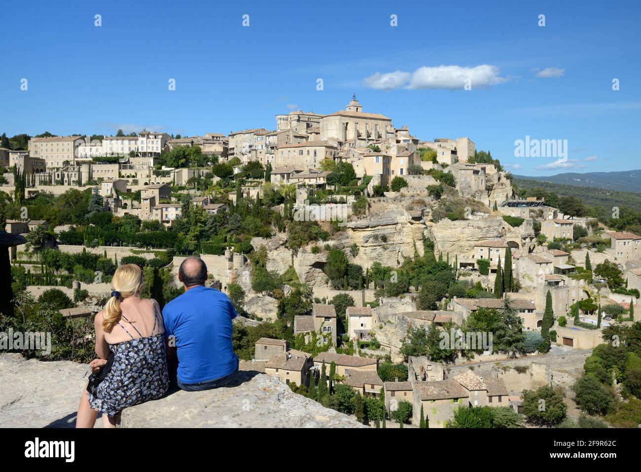 Ein paar Touristen mittleren Alters genießen die Aussicht über die Modisches Bergdorf in Gordes im Regionalpark Luberon Provence Frankreich Stockfoto