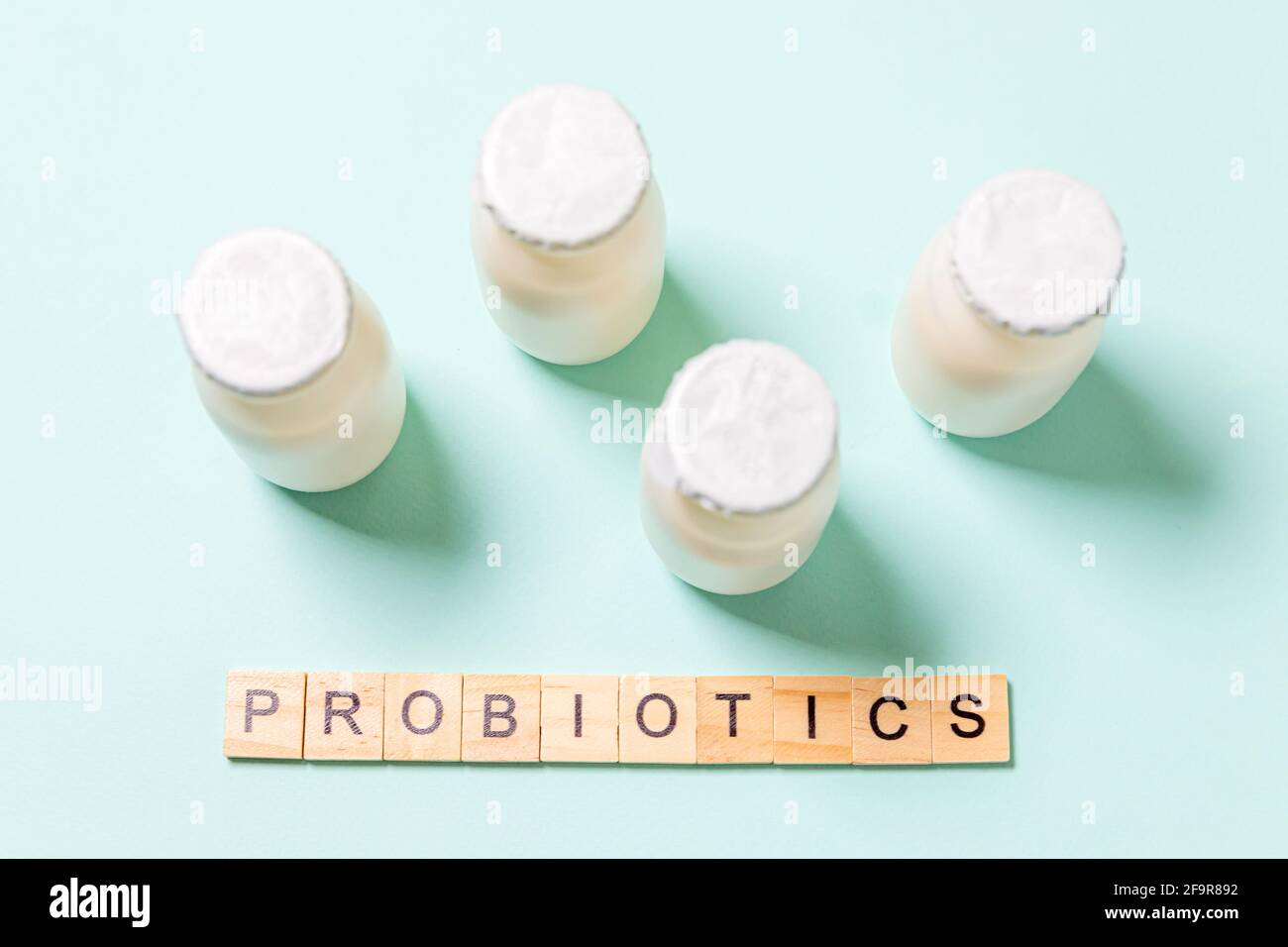 Kleine Flaschen mit Probiotika und Präbiotika Milchgetränk auf blauem Hintergrund. Herstellung mit biologisch aktiven Zusatzstoffen. Fermentation und Ernährung heilen Stockfoto