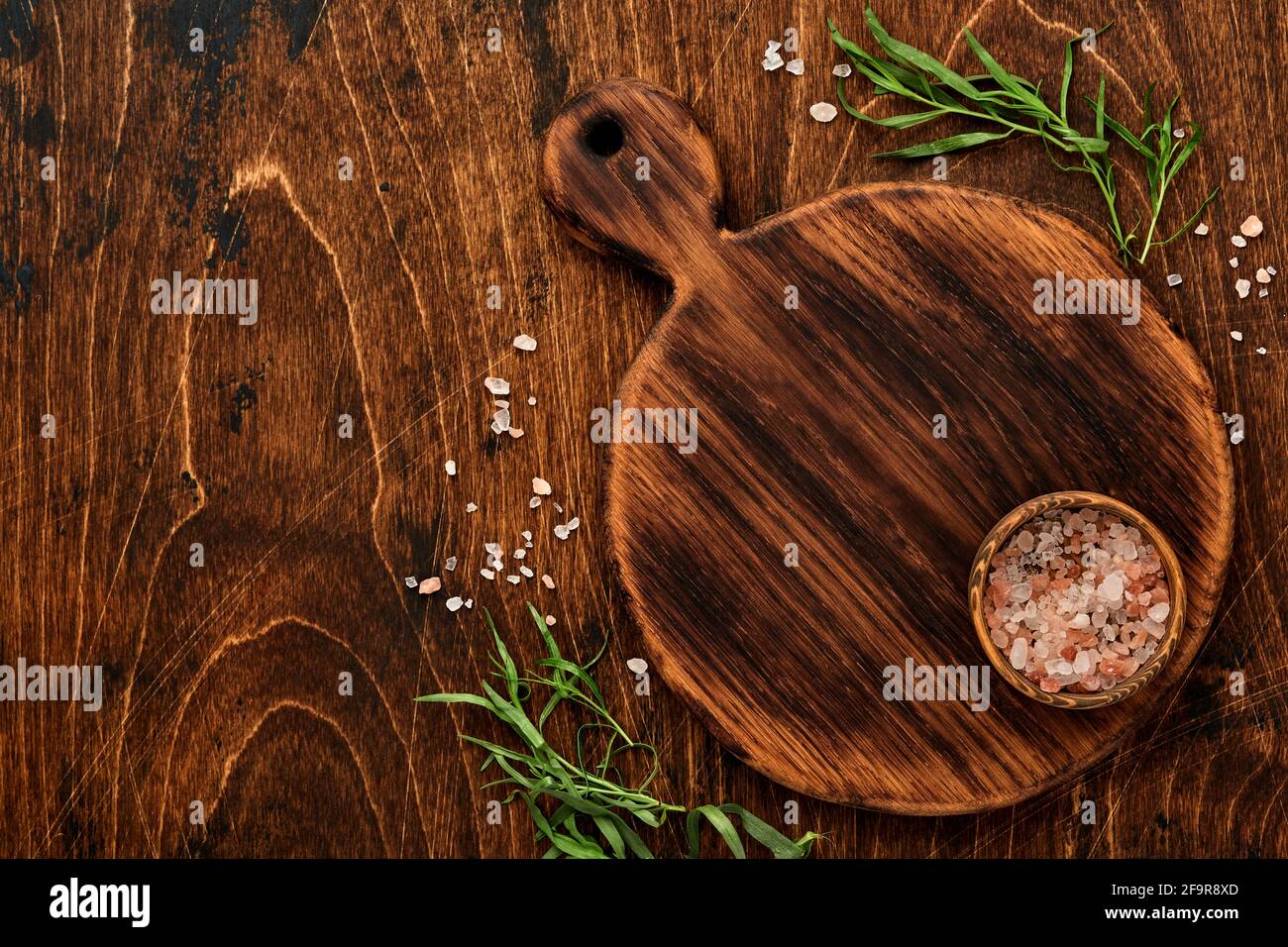 Frischer Estragon. Zweig der frischen Kräuter Gewürz-und Kochprodukte, Tomaten, Paprika, Zwiebeln und Olivenöl auf schwarzem Beton Hintergrund. Kochen Bac Stockfoto