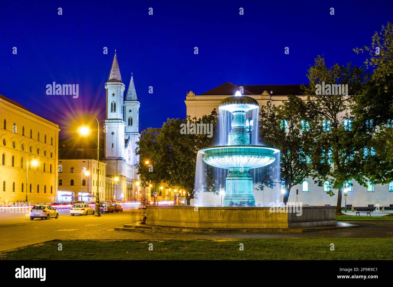 Nachtansicht eines beleuchteten Brunnens vor dem universität in münchen mit der Kirche st. ludwig im Hintergrund Stockfoto