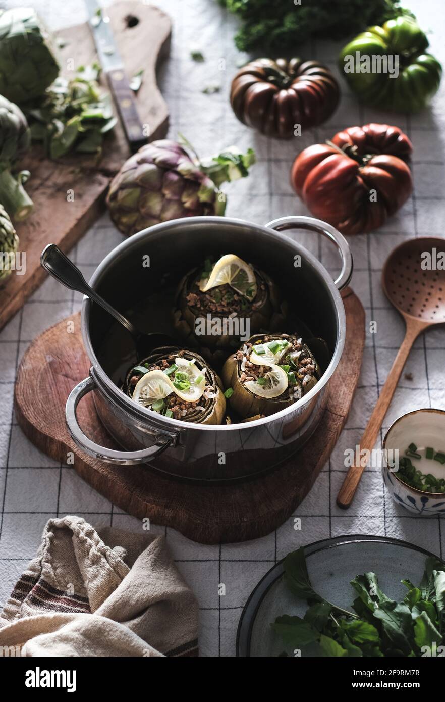 Gefüllte Artischocken im Topf auf dem Tisch mit Gemüse, ägäische Küche Stockfoto