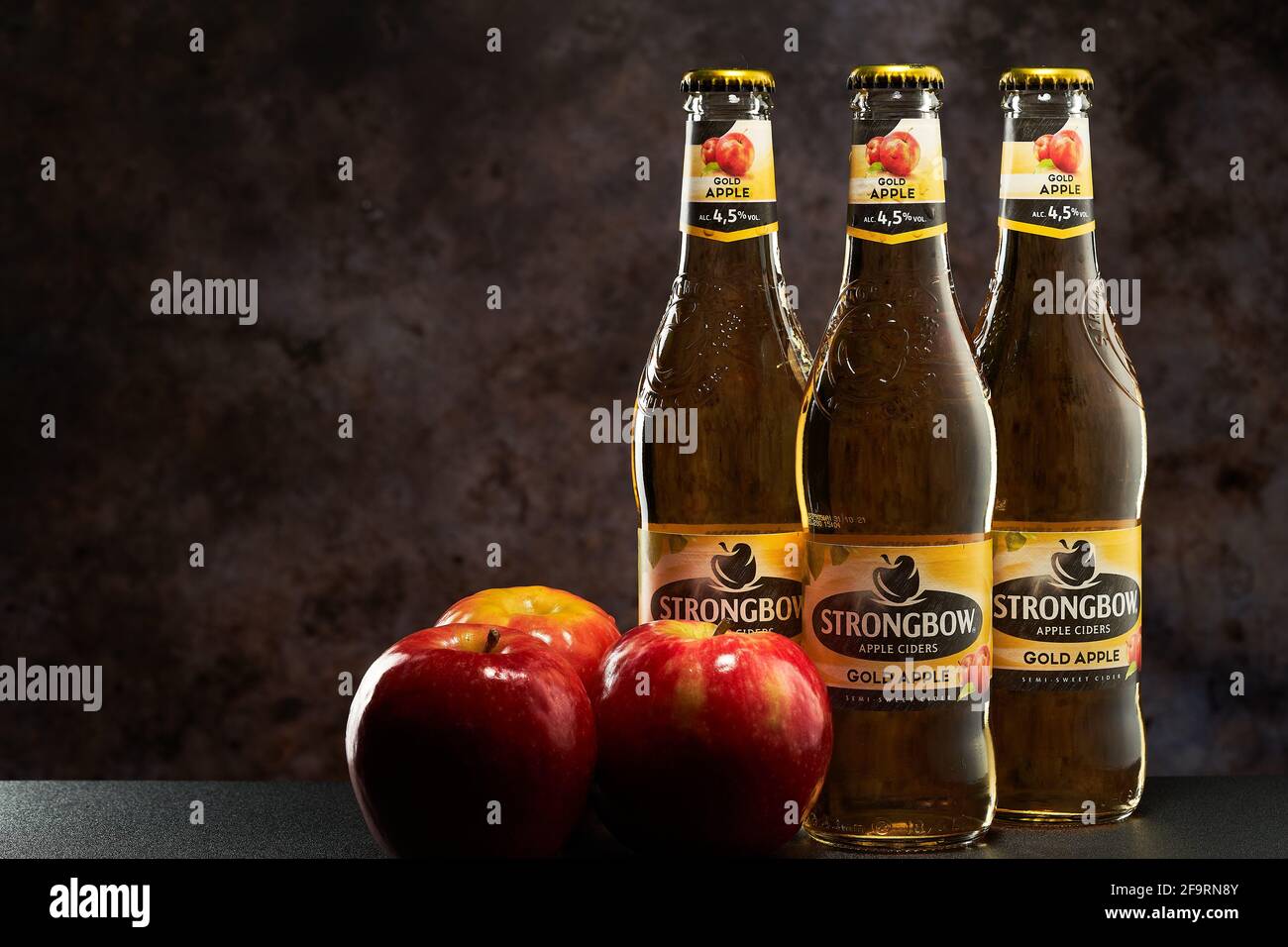 Tel-Aviv, Israel - 20.04.21.Gold Apfelwein helles alkoholisches Getränk auf dunklem Hintergrund. Drei frische rote Äpfel auf der Flaschenseite. Stockfoto