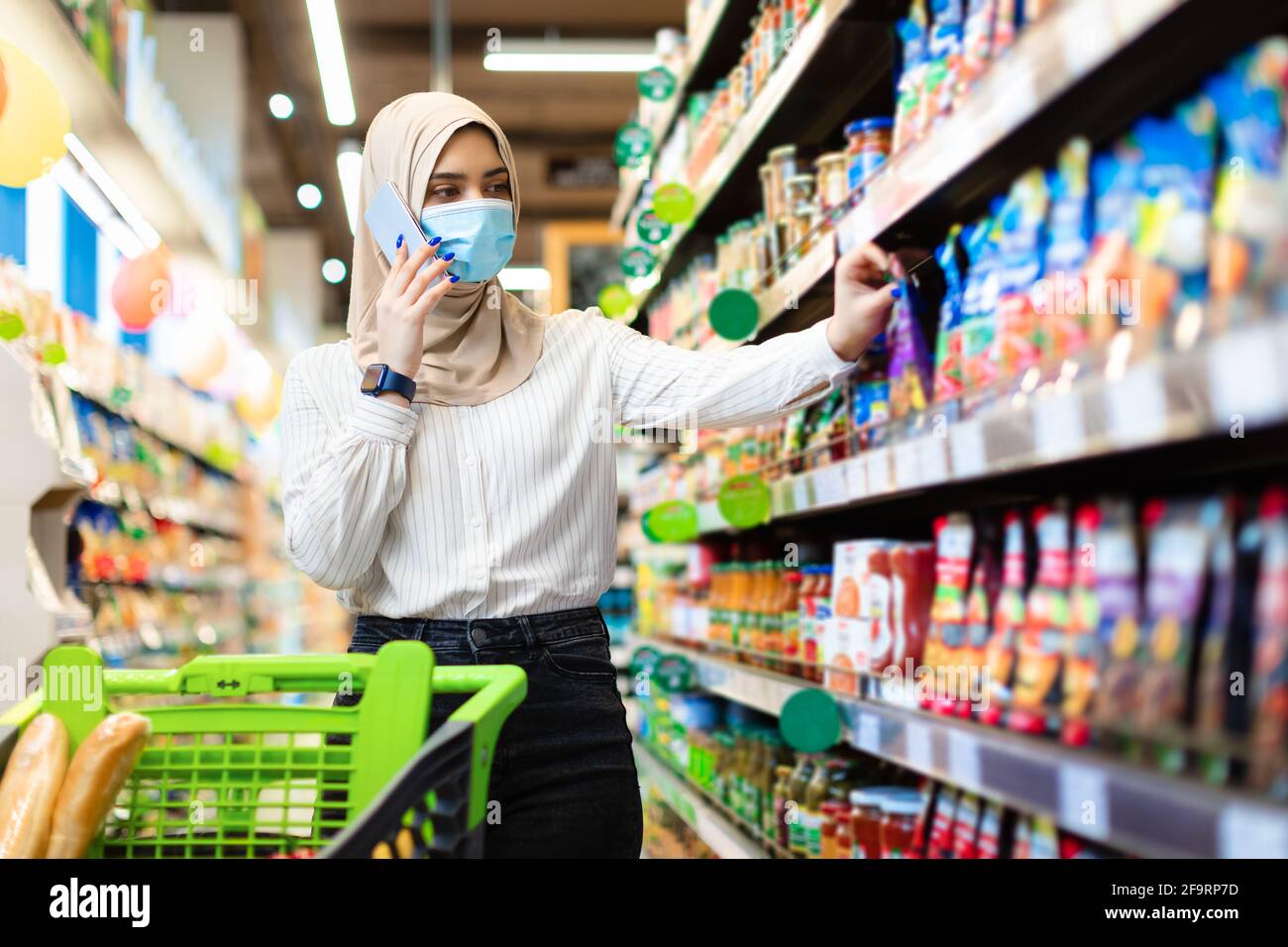 Muslimische Frau Spricht Am Telefon Lebensmittelprodukte Im Supermarkt Auswählen Stockfoto