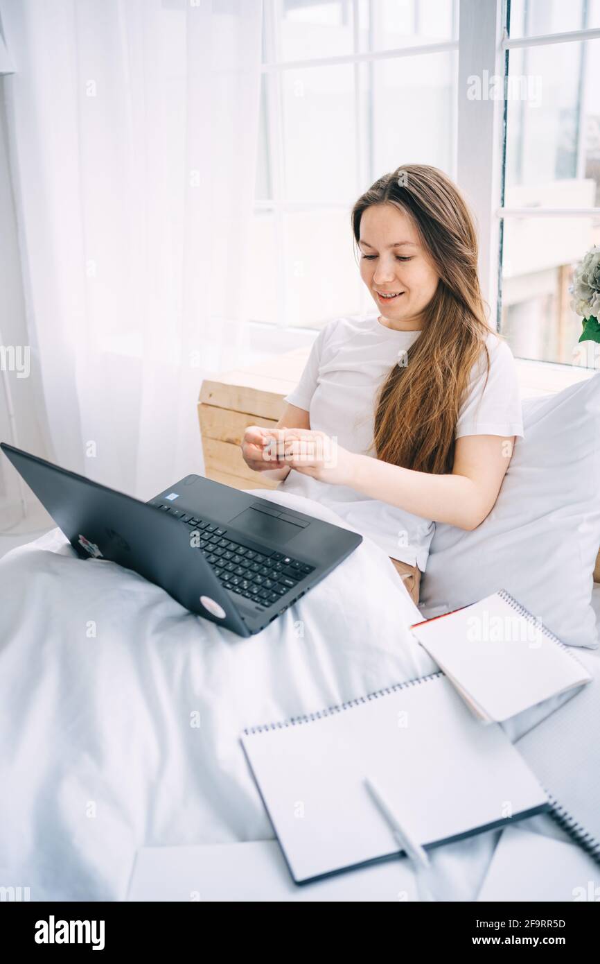 Mädchen, das im Bett an einem Laptop arbeitet Stockfoto