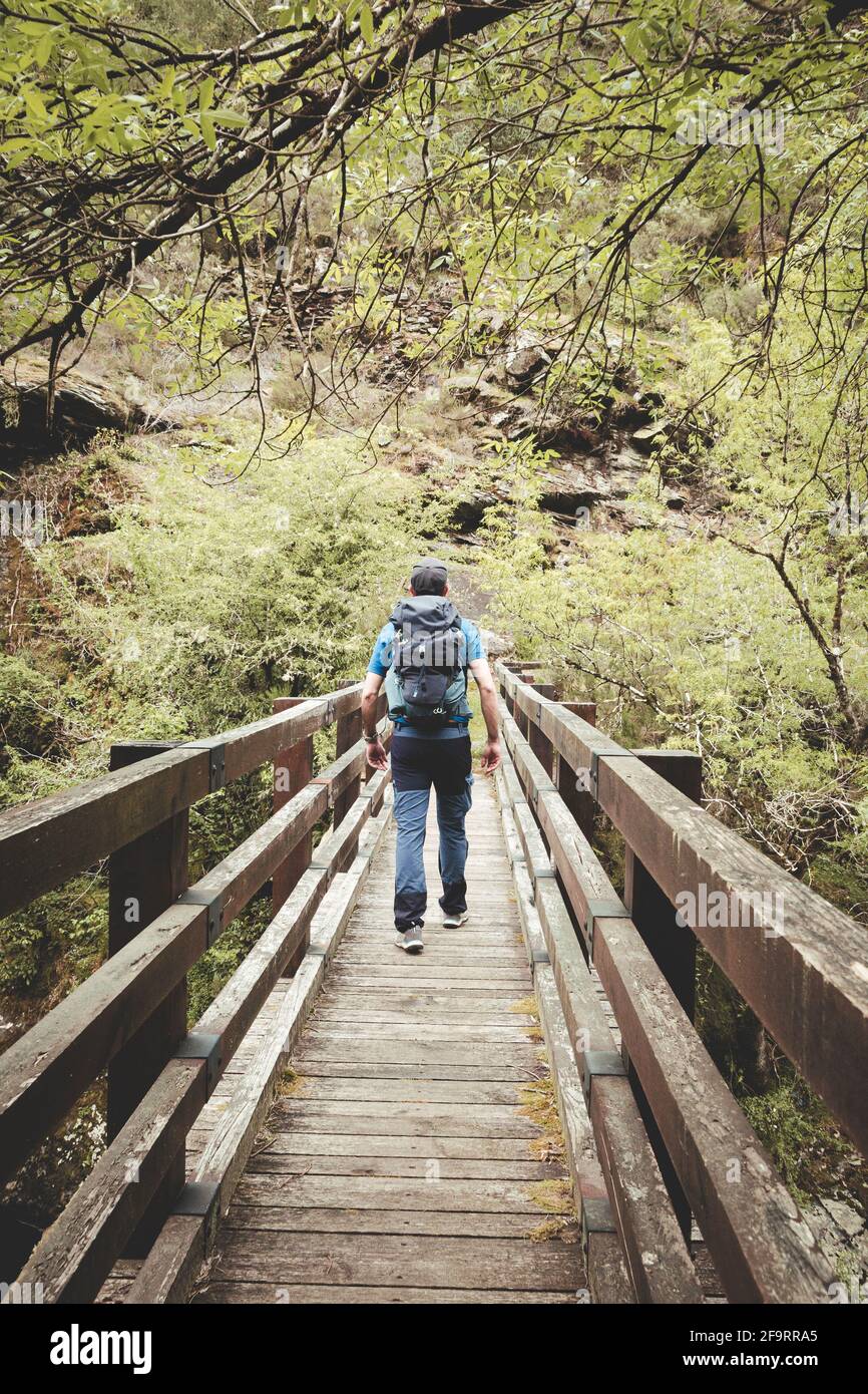 Mann mit Rucksack und Mütze über eine Brücke Stockfoto
