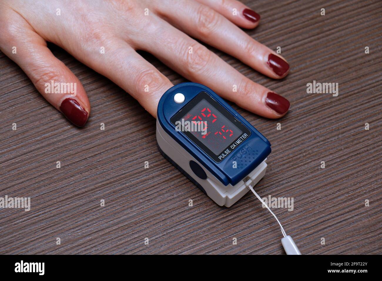 Pulsoxymeter an der weiblichen Hand, das Puls und Sauerstoff misst Sättigung in roten Blutkörperchen Stockfoto