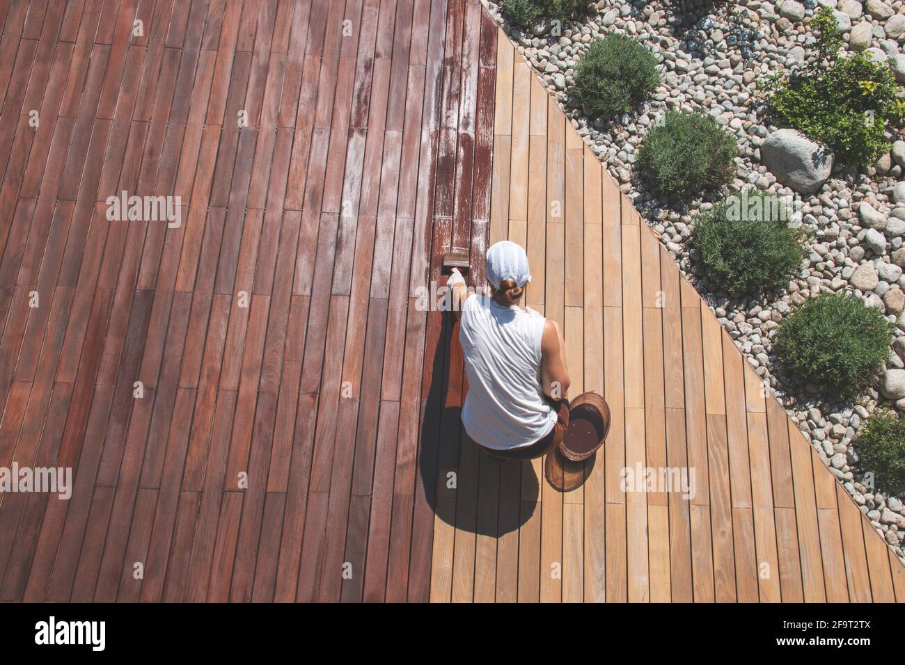 Ölauftrag von Holzdecks, Ansicht von oben über die Person, die die Terrasse einölt, Oberflächenöl von Deck oder Holzschliff Stockfoto