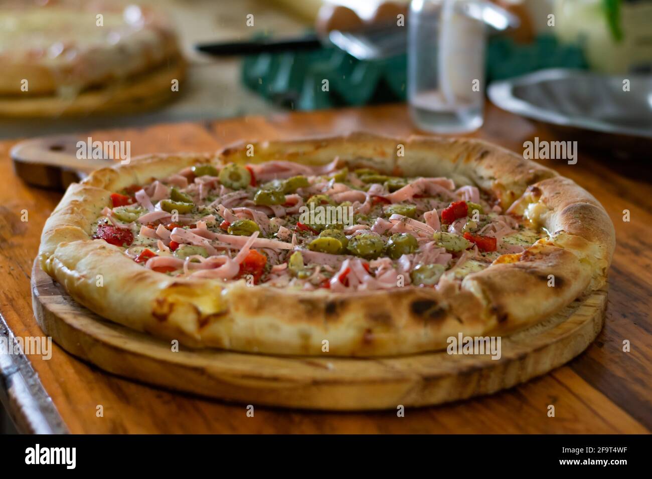 Nahaufnahme einer Pizza auf einem Holzhalter Stockfoto
