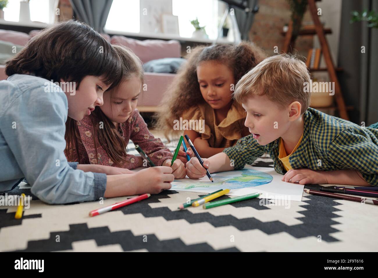 Kleine Jungen und Mädchen liegen auf dem Boden und zeichnen Ein Bild mit Bleistiften zu Hause Stockfoto