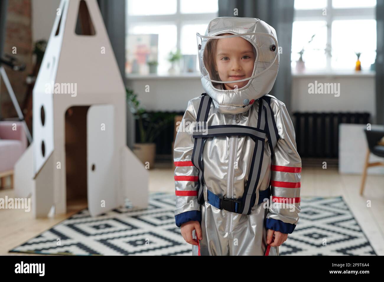 Porträt eines kleinen Mädchens im Astronautenkostüm, das vor der Kamera lächelt Während des Spielens im Raum Stockfoto