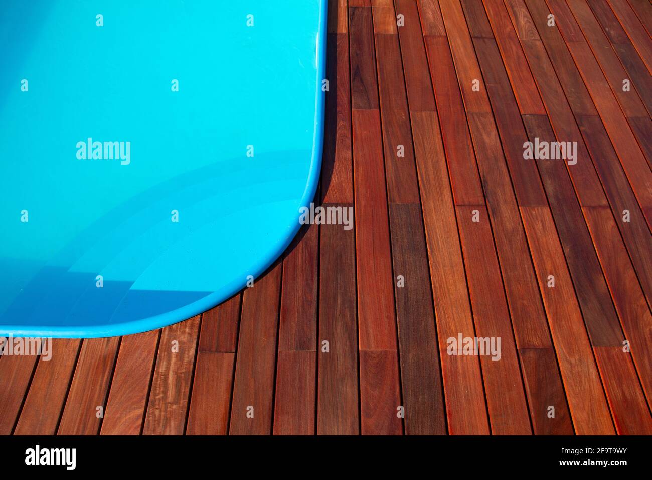 IPE Holzterrasse um den Rand des Swimmingpools. Terrassendesign am Pool, blaues Wasser im Kontrast zu tropischem Hartholz Stockfoto