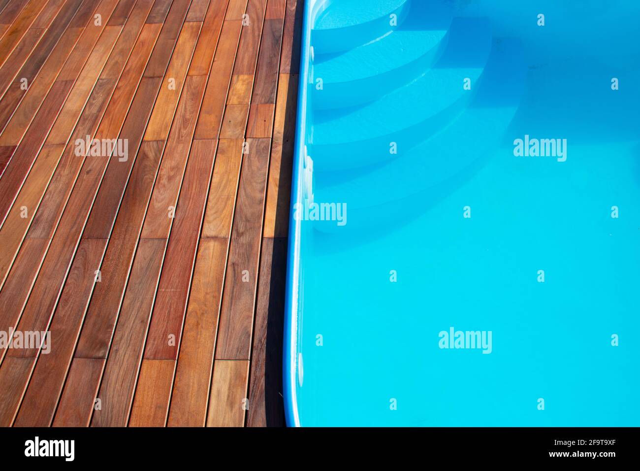IPE Holzterrasse und Swimmingpool aus nächster Nähe. Gartenterrasse am Pool, blaues Wasser im Kontrast zu tropischen Hartholzplatten. Stockfoto