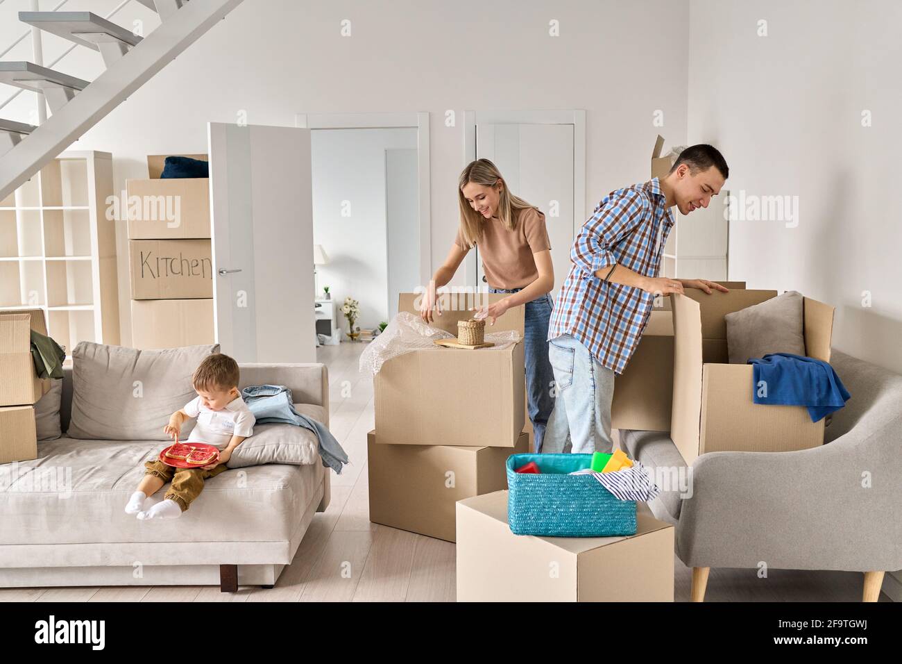 Glückliche Familie neue Hausbesitzer mit Kind Auspacken Pappkartons am Umzugstag. Stockfoto