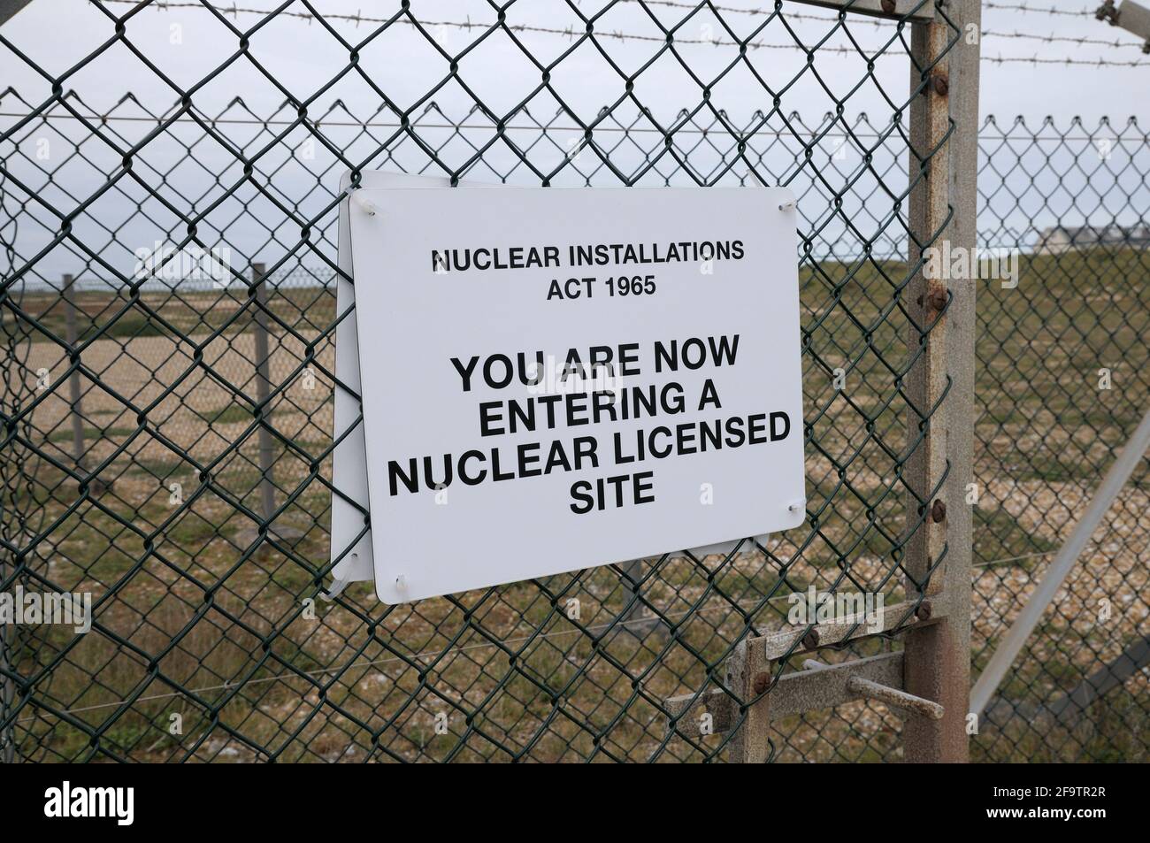 Warnschild an einem Drahtzaun mit der Meldung „Sie betreten jetzt einen nuklearen Standort“ gemäß dem Nuclear Installations Act 1965, Dungeness, Kent, Großbritannien Stockfoto