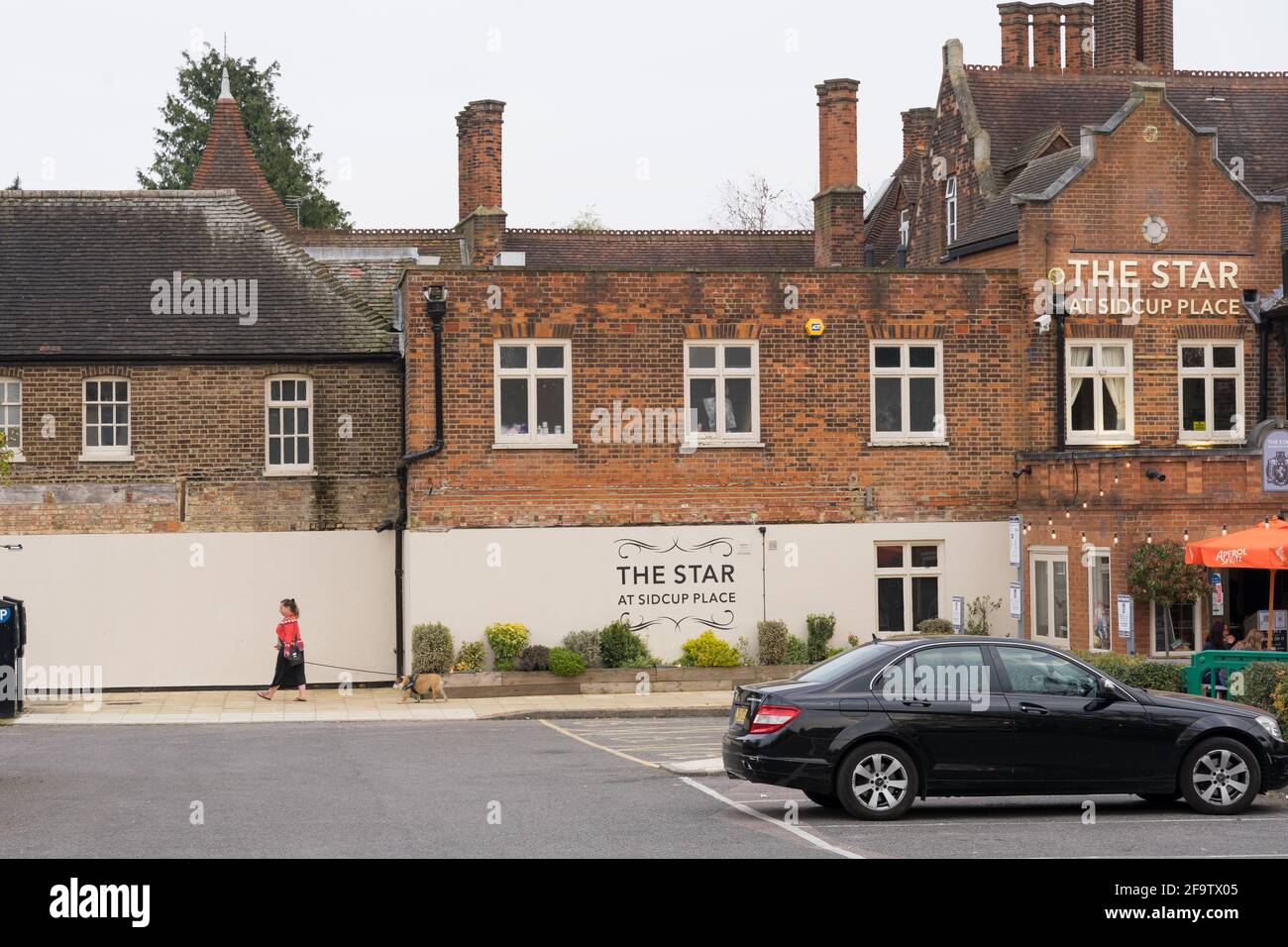 Frau geht mit ihrem Hund aus dem Pub The Star am sidcup Place, Kent, Parkplatz Stockfoto