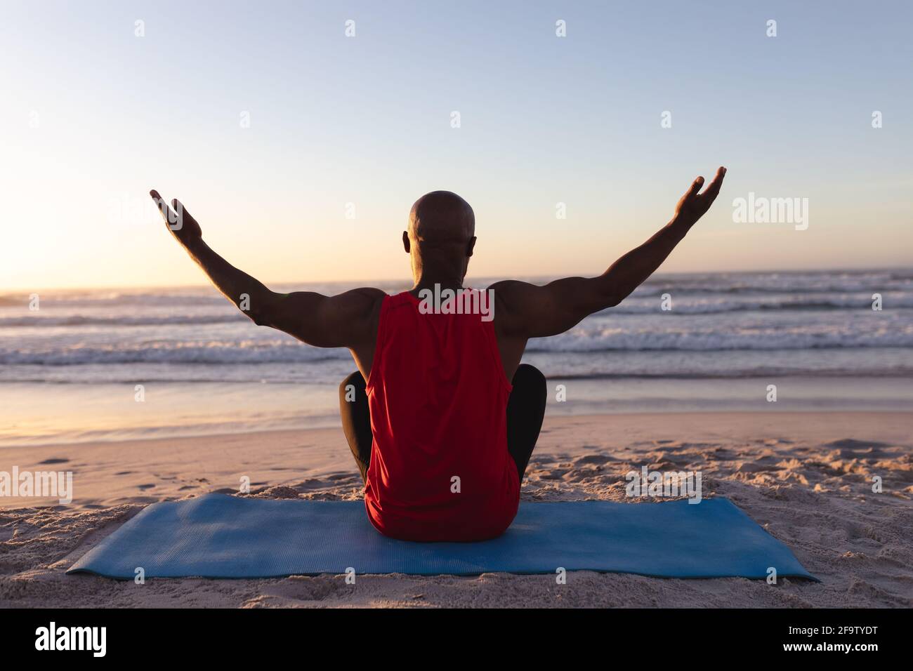 Rückansicht eines älteren afroamerikanischen Mannes mit breiten Armen Geöffnet Yoga am Strand üben Stockfoto
