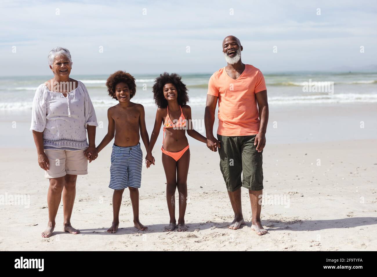 Porträt afroamerikanischer Großeltern und Enkelkinder mit lächelnden Händen Am Strand Stockfoto