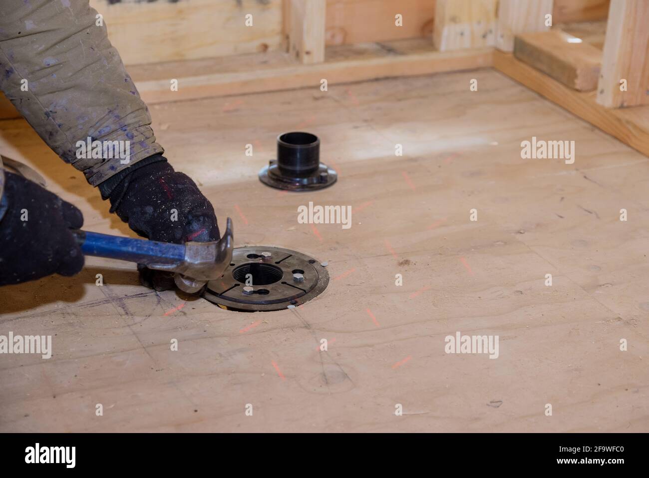 Nageln Dusche Abfluss auf Sperrholzboden für neue Sanitär installieren Stockfoto