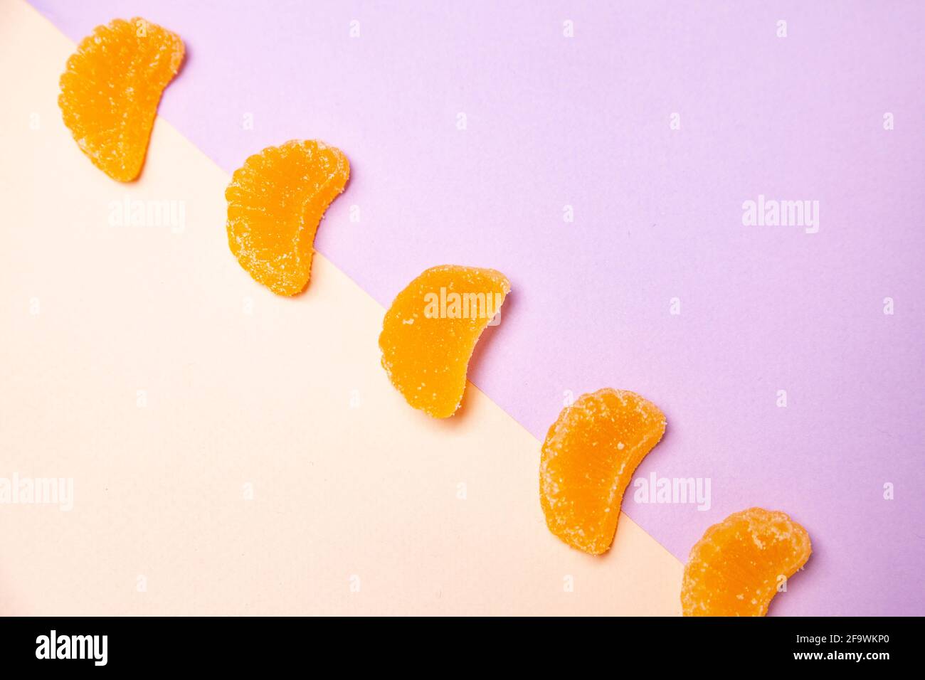 Draufsicht minimalistisches Layout von Orangensaft-Gelee-Bonbons In diagonaler Reihe auf mehrfarbigem Hintergrund angeordnet Stockfoto